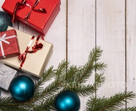 Christmas flat lay with presents, blue tree ornaments and pine branches on a white wooden background. Copy space on the right.