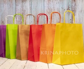 A rainbow of colorful paper bags on a shabby chic wooden table for your joyful shopping. Space for logo or a script on the yellow bag.