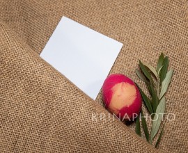 Coloured egg and an olive branch on a jute cloth with a blanck card for Easter thought.
