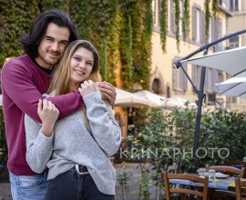 Young couple traveling to Rome. Beautiful man hugs his girlfriend. In the background a street in the historic center with a building covered with ivy. Concept of love and holiday.