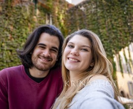 Beautiful couple traveling to Rome. Young couple takes a selfie in a street in the historic center. In the background a building covered with ivy.
