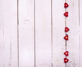 A string of small lights inside red hearts on a white wooden background.  Shabby chic, rustic and intimate atmosphere.